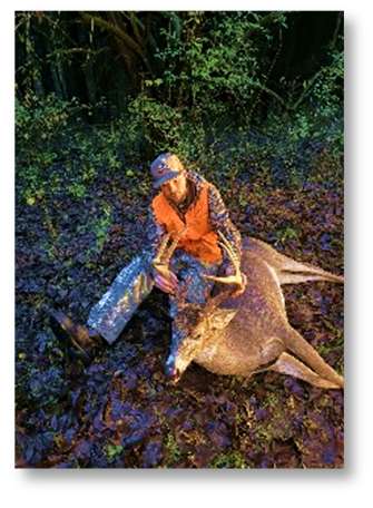 Hunter in blaze orange with a whitetail buck